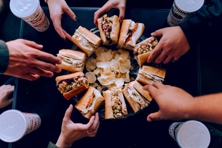 People reaching for Capriotti's sandwiches